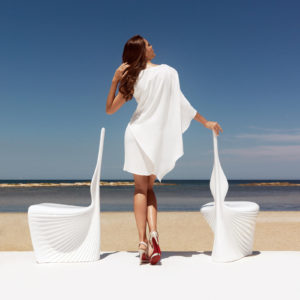 A woman with two white Biophilia dining chairs by Vondom.