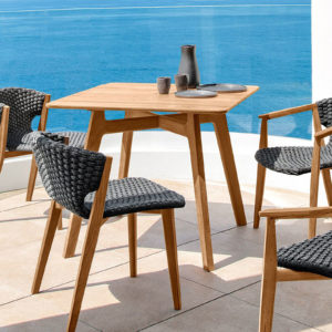 Ethimo's Knit range small dining table with dining chairs by the sea.